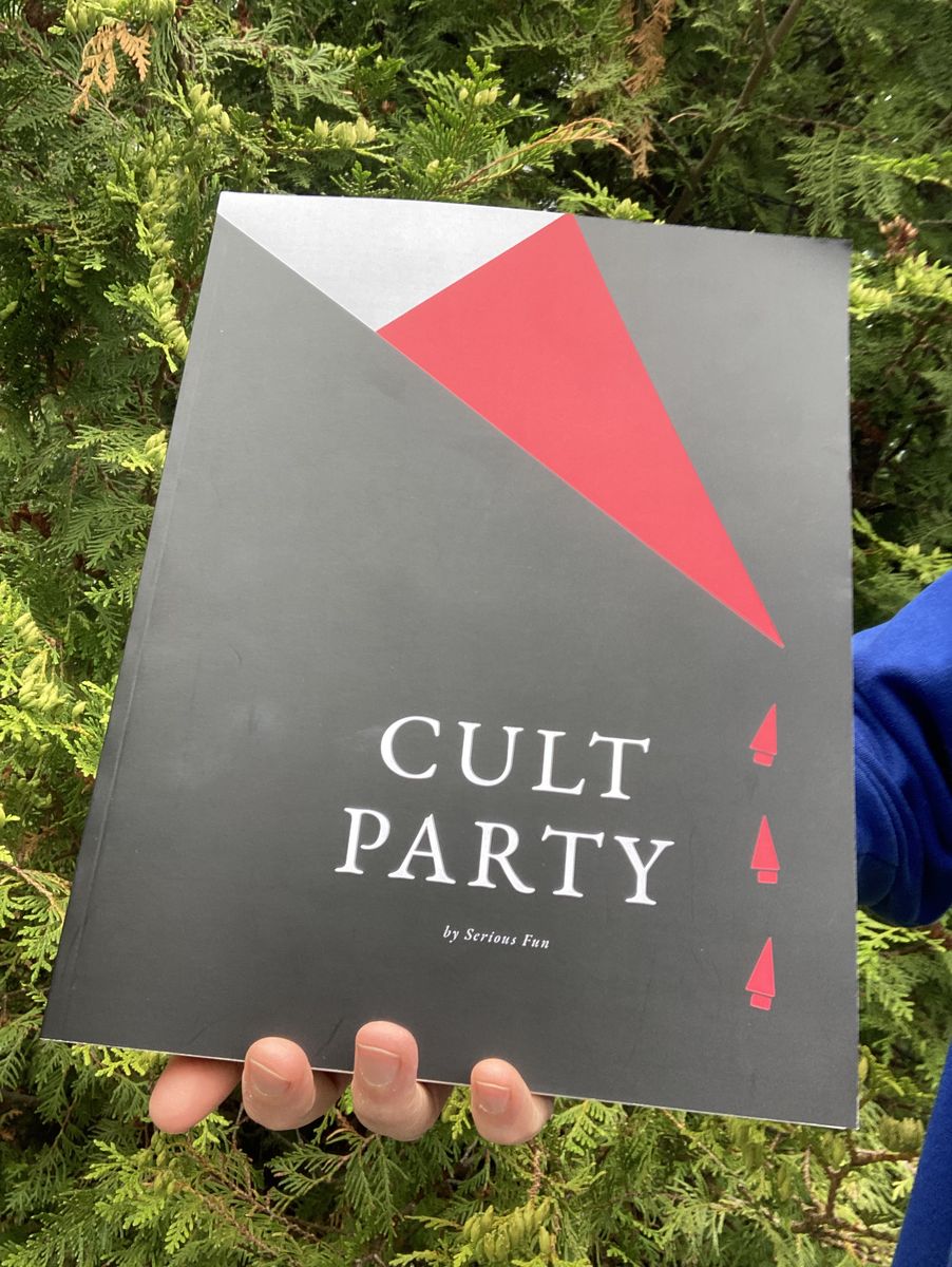 The Cult Party guide, held up against a hedge